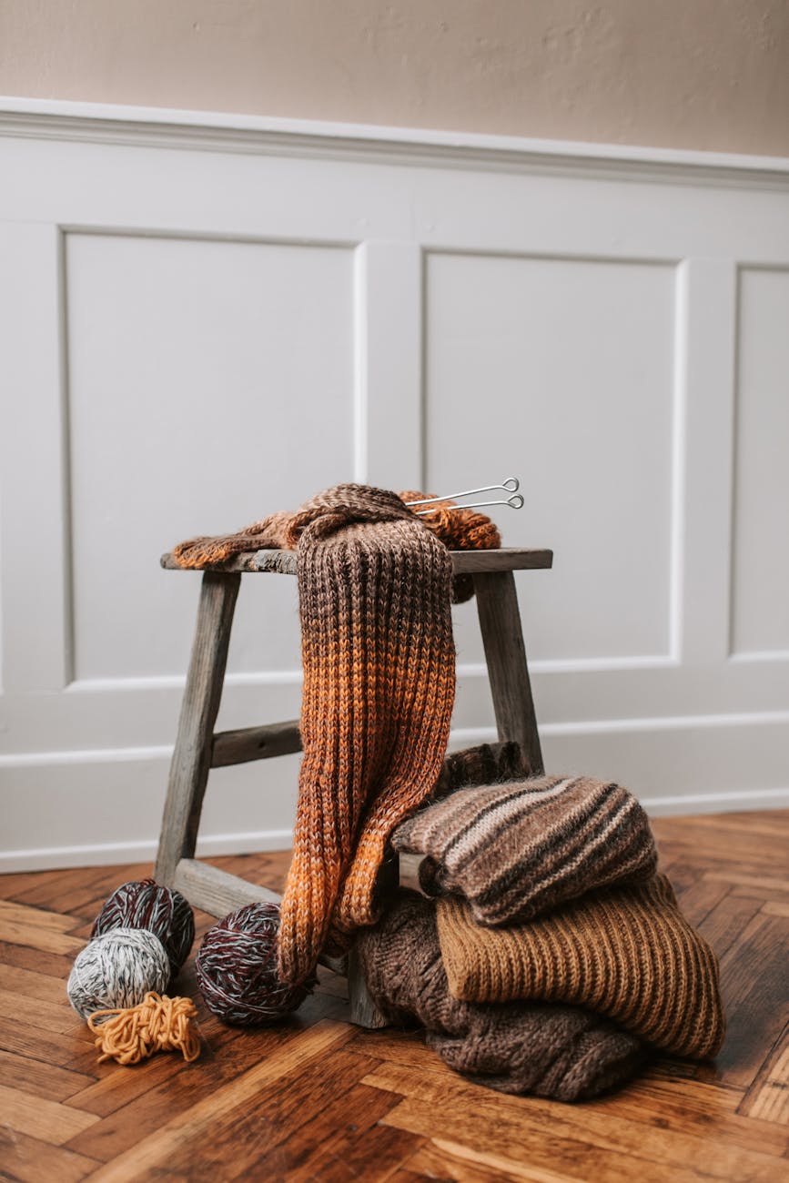 Layered chunky knit throws artfully placed by a wooden stool